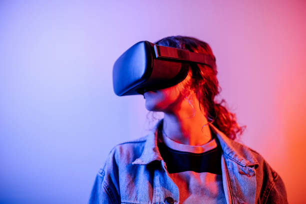 istock Young hipster woman wearing virtual reality goggles in studio with neon lights 1452486117