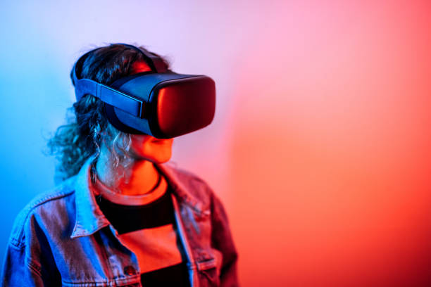 istock Young hipster woman wearing virtual reality goggles in studio with neon lights 1452486140