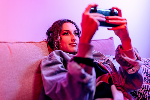 Young woman playing online smartphone video game in her apartment