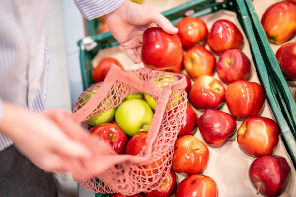 istock Unrecognizable woman with reusable eco bag shopping apples 1452486903