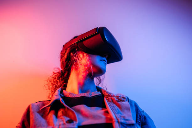istock Young black woman playing game using VR glasses, enjoying 360 degree virtual reality headset for gaming, isolated on background with neon lights 1452487068