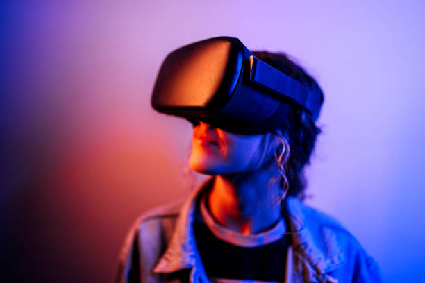 istock Young hipster woman wearing virtual reality goggles in studio with neon lights 1452487136