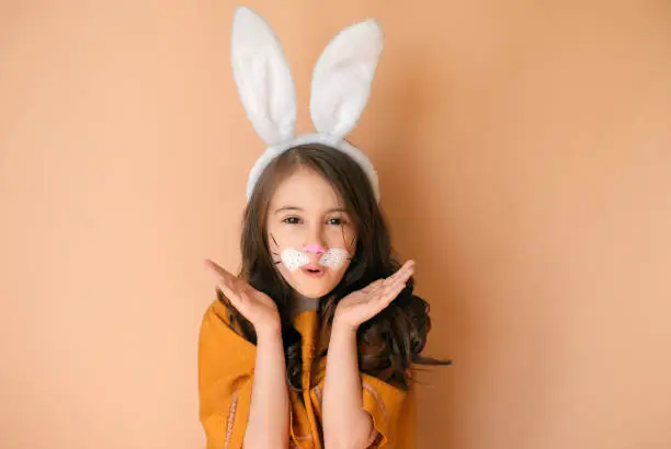 A girl dressed up as a hare with big rabbit ears enthusiastically shouts making a gesture with her hand. Symbol of 2023 new year according to the Eastern calendar