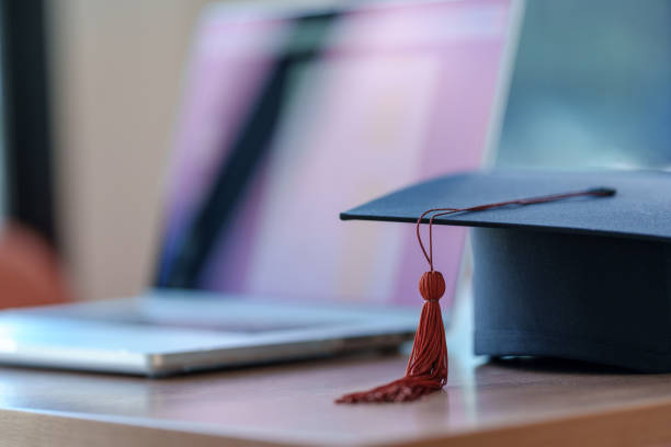 istock Graduation cap with laptop pace on wood table background. 1452491315