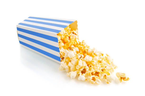 Cтоковое фото Вкусный сырный попкорн, выпадающий из синего полосатого картонного ведра, изолированного на белом фоне