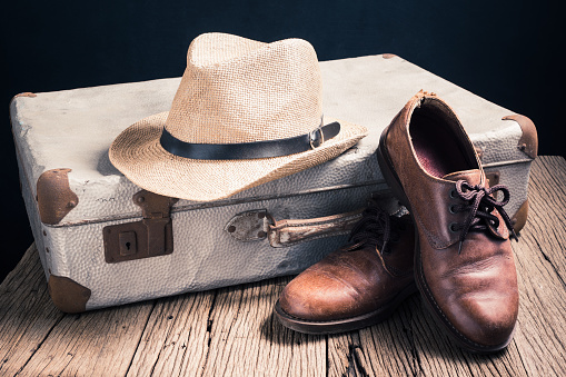 still life photography : old things, hat, leather shoes and suitcase on old wood in traveler concept