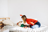 The beautiful wonan playing with her cute dog on the bed on the Christmas