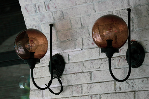 Retro vintage glass lamp bulb with brown glass color attached to white painted brick wall.