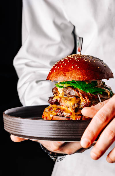istock chef holding big triple burger on a tray in hand 1452497654