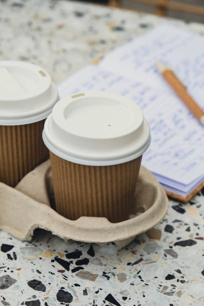 istock Two paper cups with lid for tea to go. Coffee take away on the table. Take-out coffees with brown paper cup holder. Brown safety cardboard collars. Cardboard tray 1452497792