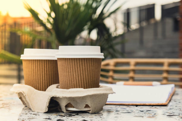 istock Two paper cups with lid for tea to go. Coffee take away on the table. Take-out coffees with brown paper cup holder. Brown safety cardboard collars. Cardboard tray 1452497860