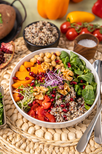 Vegan quinoa salad bowl with seasonal winter vegetables, sweet potatoes, chickpeas, sprouts and pomegranate