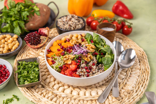 Vegan quinoa salad bowl with seasonal winter vegetables, sweet potatoes, chickpeas, sprouts and pomegranate stock photo
