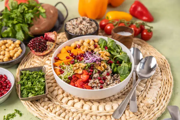 Vegan quinoa salad bowl with seasonal winter vegetables, sweet potatoes, chickpeas, sprouts and pomegranate