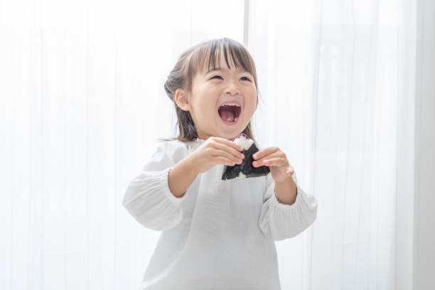 Cute asian child eating rice ball