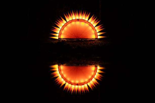 Artificial fantastic sun with sun rays or flames rising or setting reflecting in the water with a black background