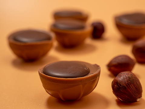 Chocolate candies on an orange background. Sweets with caramel. Round chocolates. Close-up.