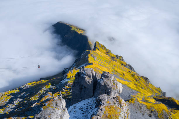 mountains and clouds in the valley. natural landscape high in the mountains. cableway in the mountains. transportation. the cable car descends into the mountain valley. - switzerland cold green rock imagens e fotografias de stock