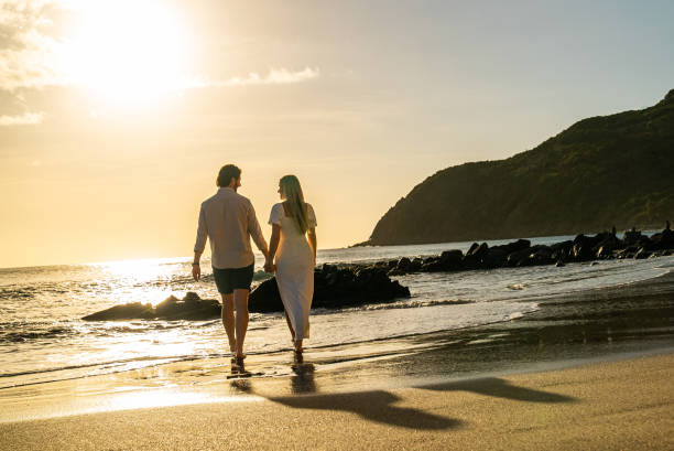 istock Picturesque romantic couple walking on an empty tropical beach during the sunset on a remote island 1452510665