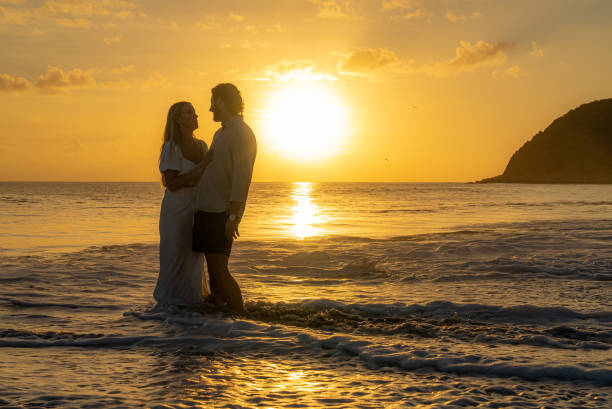 istock Young couple standing in water holding each other during the sunset 1452510736