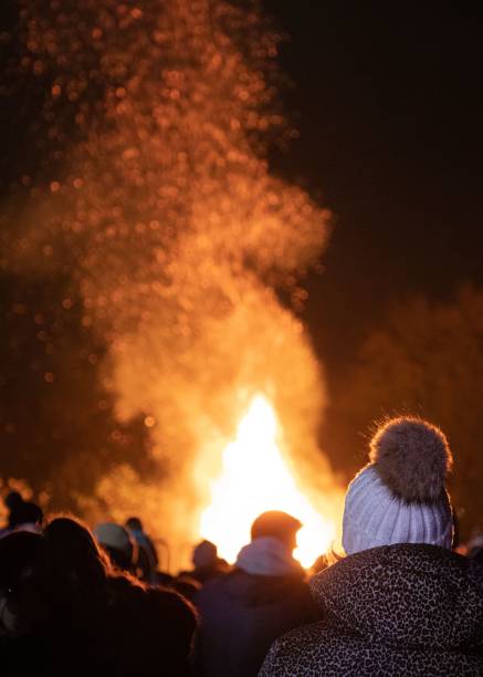 istock Vertical view of people standing before a roaring bonfire flames at night 1452515136