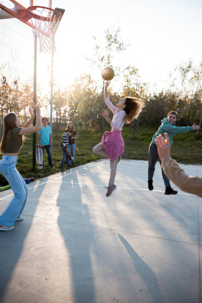 teenager spielen basketball auf einem sportplatz - basketball teenager nature outdoors stock-fotos und bilder
