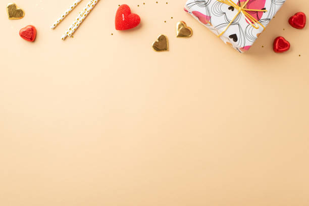 koncepcja walentynkowa. top view zdjęcie prezentowego pudełka cukierki w kształcie serca, słomki, świeca i złote cekiny na izolowanym pastelowym beżowym tle z przestrzenią kopiowania - valentines day candy chocolate candy heart shape zdjęcia i obrazy z banku zdjęć