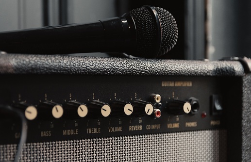 A closeup shot of a microphone on a retro guitar amplifier in a studio
