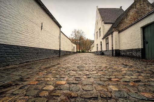 Bruges, Belgium – December 22, 2022: A closeup shot of a stone ground and buildings in a quiet neighborhood on an autumn day