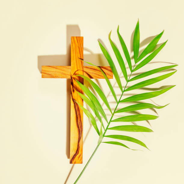 istock Wooden cross with palm leaf on light background 1452519539