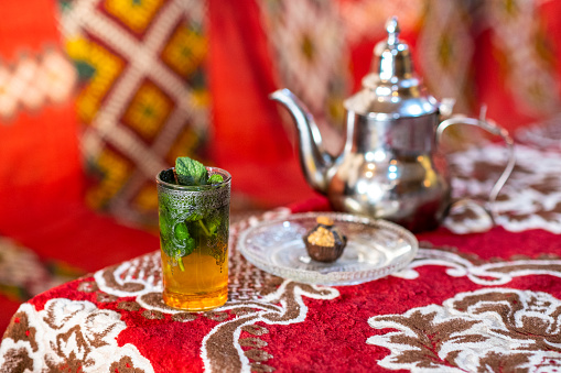 Still life of a mint tea served with a typical almond pastry on a red carpet in Morocco. Tea drinking in Morocco is a daily and popular custom.
