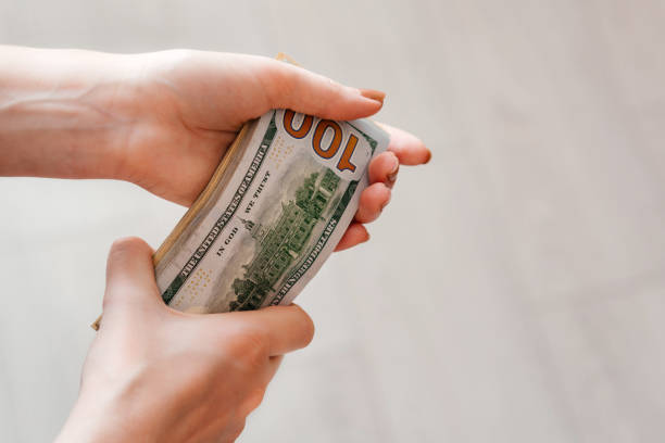 istock A woman hand holds a stack of 100 dollar bills 1452520000