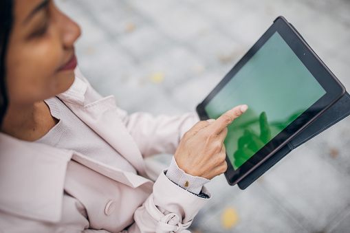 Modern black woman using digital tablet on the street in city.