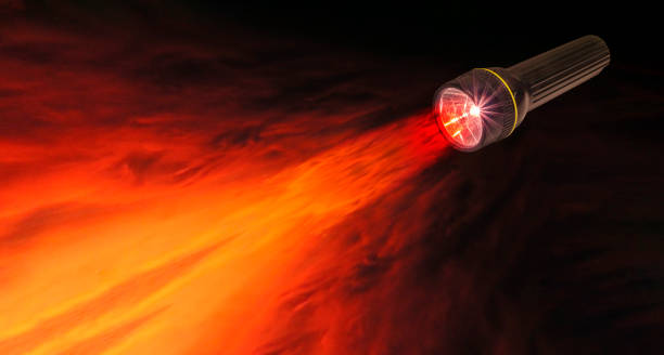 istock Black flashlight switched on and sending a beam onto a red and yellow sunset sky background. Concept shedding light, bright idea, innovation, security. Copy space. Clipping path on flashlight 1452523992