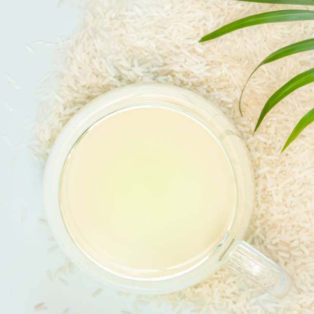 istock Cup of rice milk, rice seeds and palm leaf on a blue background 1452525067