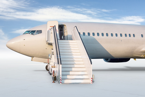 Close-up of passenger jet plane with aircraft steps isolated on bright background with sky