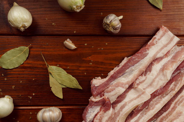 istock Raw bacon on a wooden table with onion, garlic and spices 1452527221