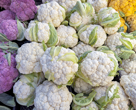 Fresh pink, yellow and white cauliflowers in a market stall