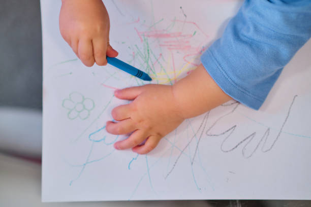 istock Toddler drawing on white paper with crayons 1452533210
