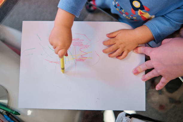istock Toddler drawing on white paper with crayons 1452533261