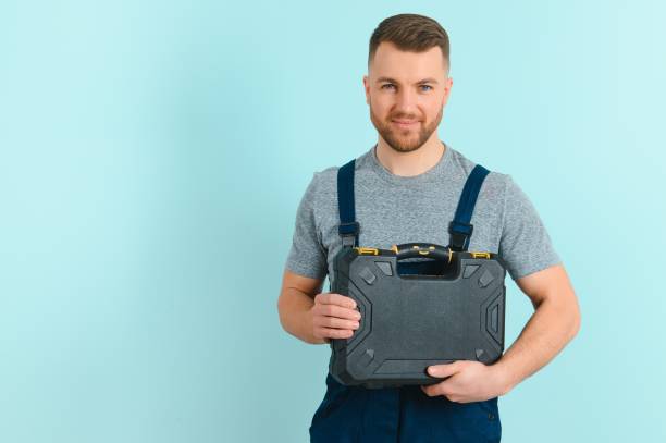 Portrait of smiling worker in blue uniform isolated on blue background