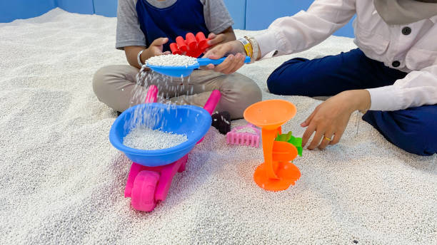 son and older sister playing sand in the indoor