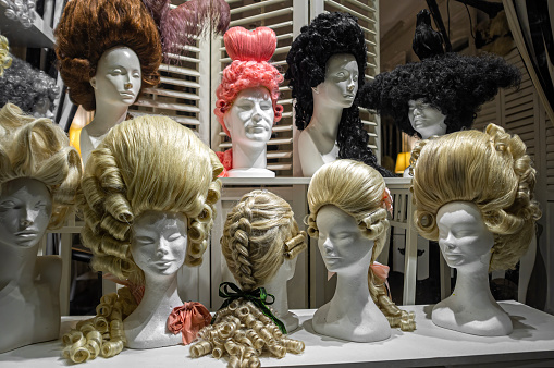 Female mannequin heads with wigs, behind a wig shop window