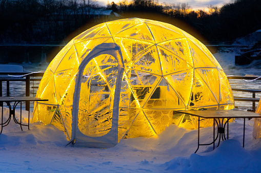 Glowing outdoor clear plastic geodesic igloo for family get togethers outdoors in Winter.