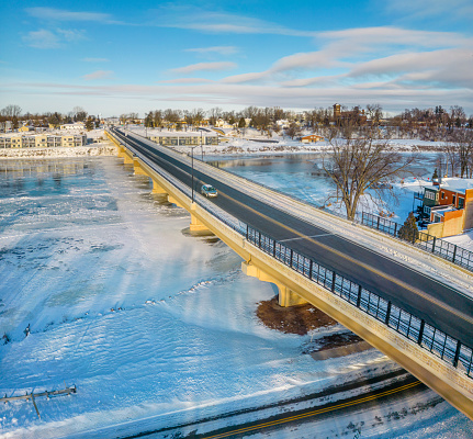Scenic bridge crossing wide river covered in ice and snow.