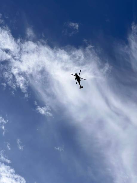 istock Silhouette of a helicopter flying in the blue sky with white clouds 1452545609