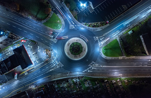A long exposure shot of traffic on the traffic circle with illuminated street lanterns in the night