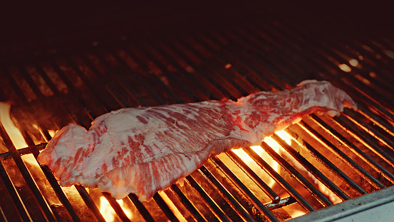 Grilled bone-in pork chop, pork steak, tomahawk in spicy marinade on a flaming gril plate, close-up. Barbecue, bbq meat