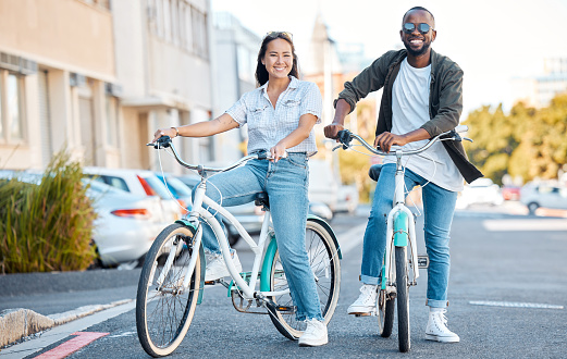 Bike, couple and travel with a black man and asian woman cycling in the city for sightseeing or adventure. Bicycle, carbon footprint and love with a male and female dating in an urban town together
