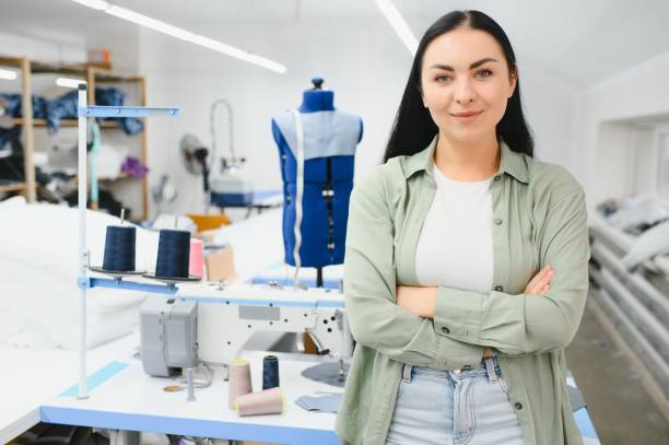 istock Positive young woman sewing with professional machine at workshop. 1452550743